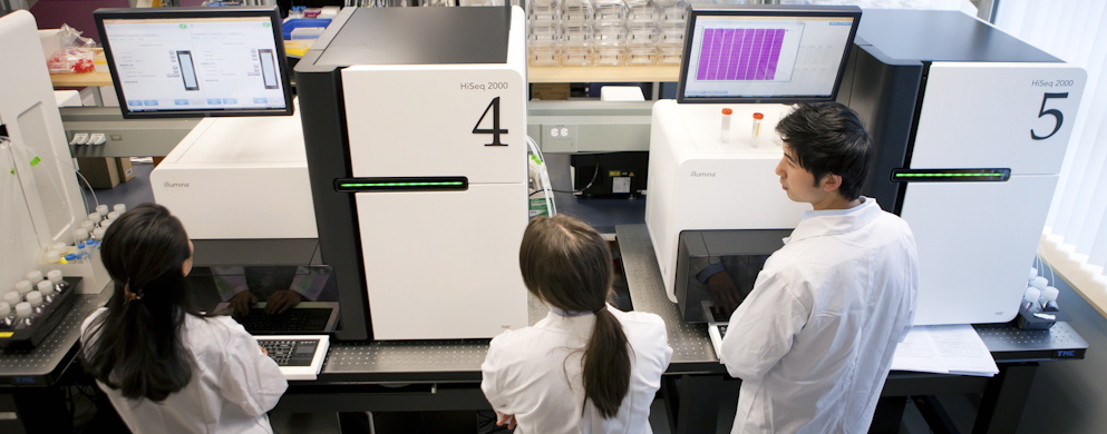 Three lab techs watch the DNA Sequencers in action